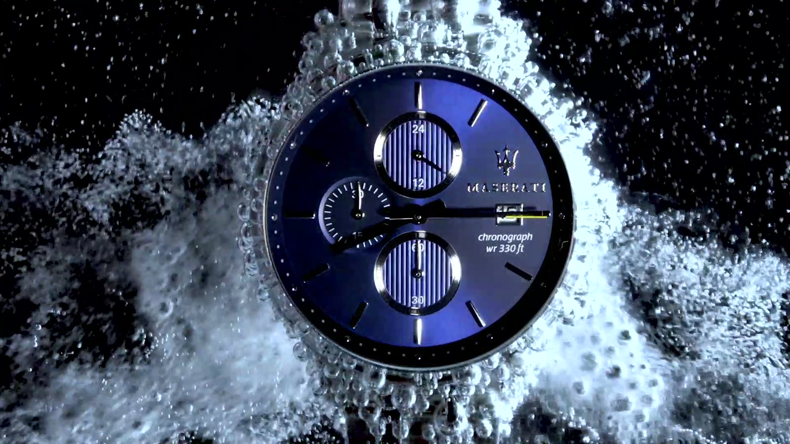 Maserati chronograph watch amid a burst of water droplets, lit against black